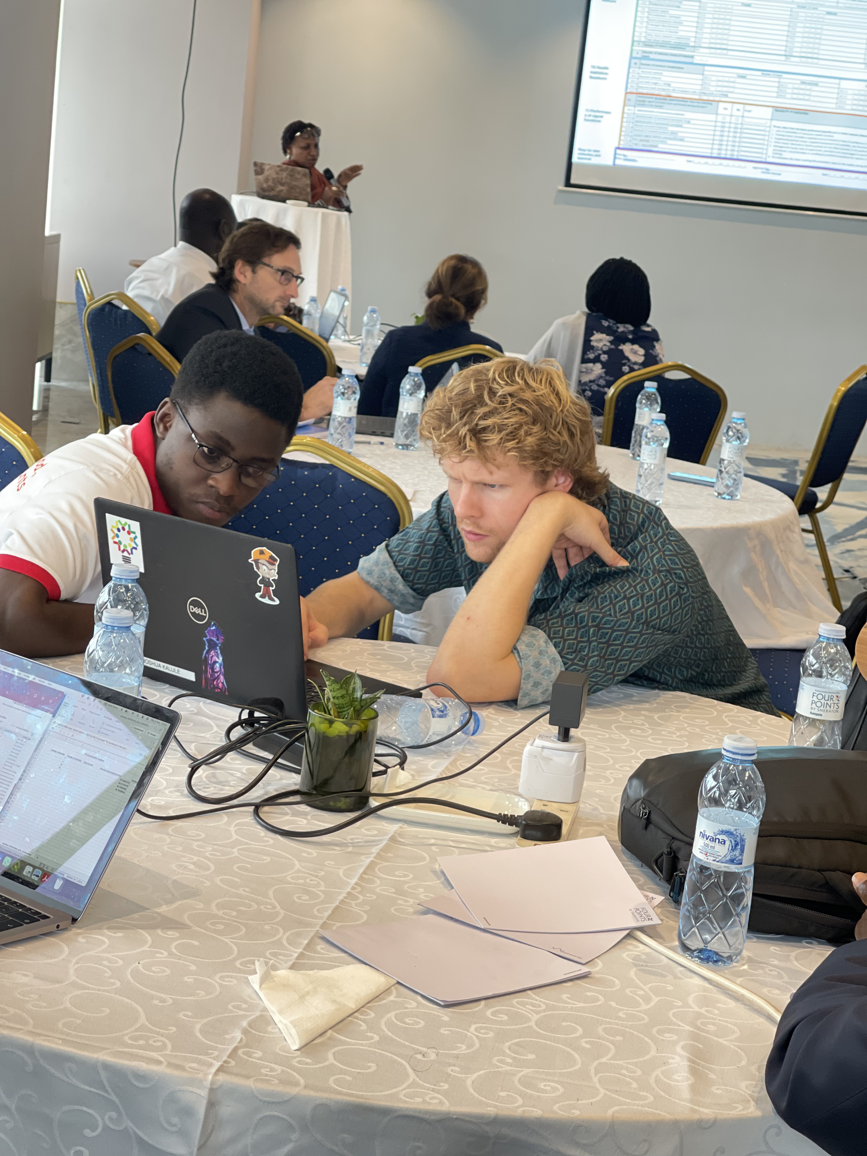 Two people working together on a laptop during a workshop session on healthcare accessibility modelling in Kampala, Uganda
